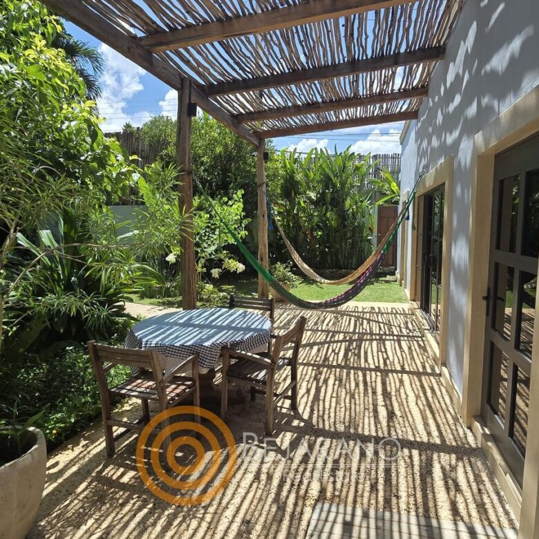 Corredor exterior con hamaca y comedor bajo pérgola de carrizo