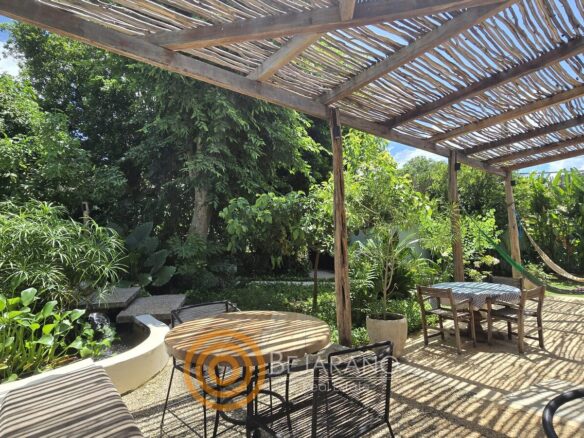 Terraza con mesas de madera frente al jardín tropical