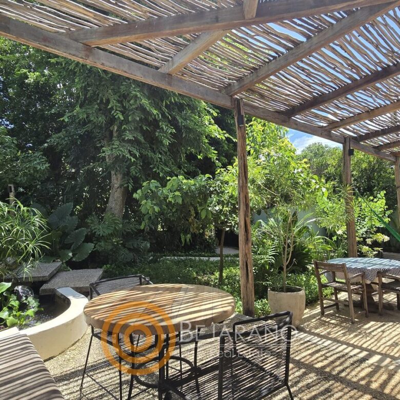 Terraza con mesas de madera frente al jardín tropical