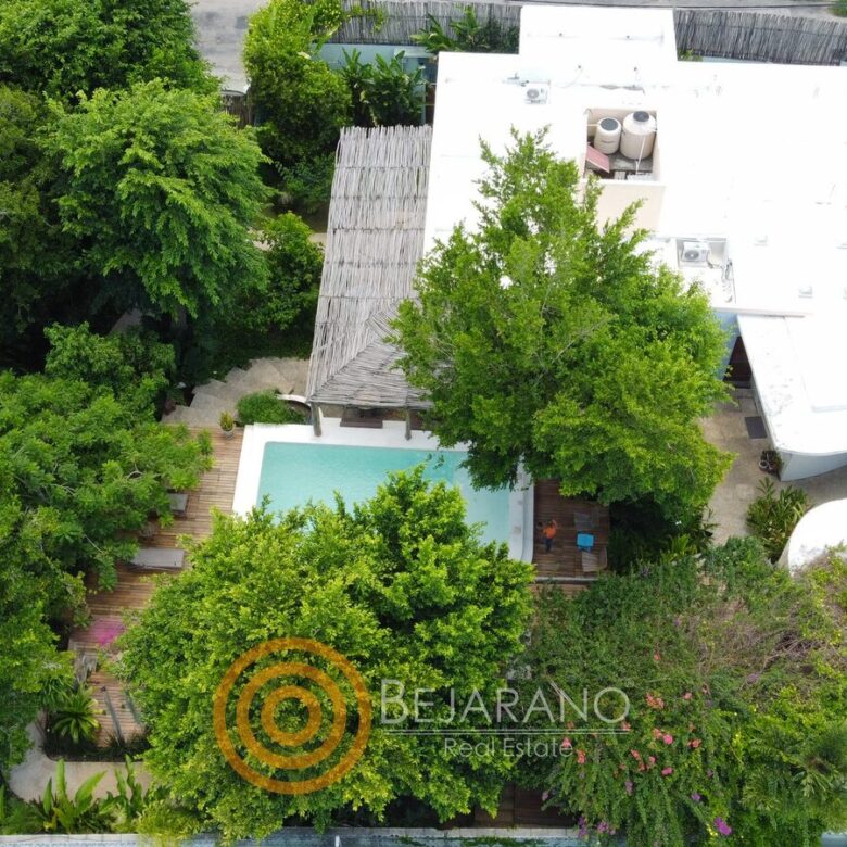 Toma de dron del jardín arbolado, la alberca y las azoteas