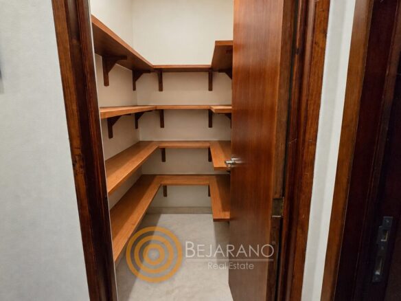 Despensa con repisas de madera junto a la cocina